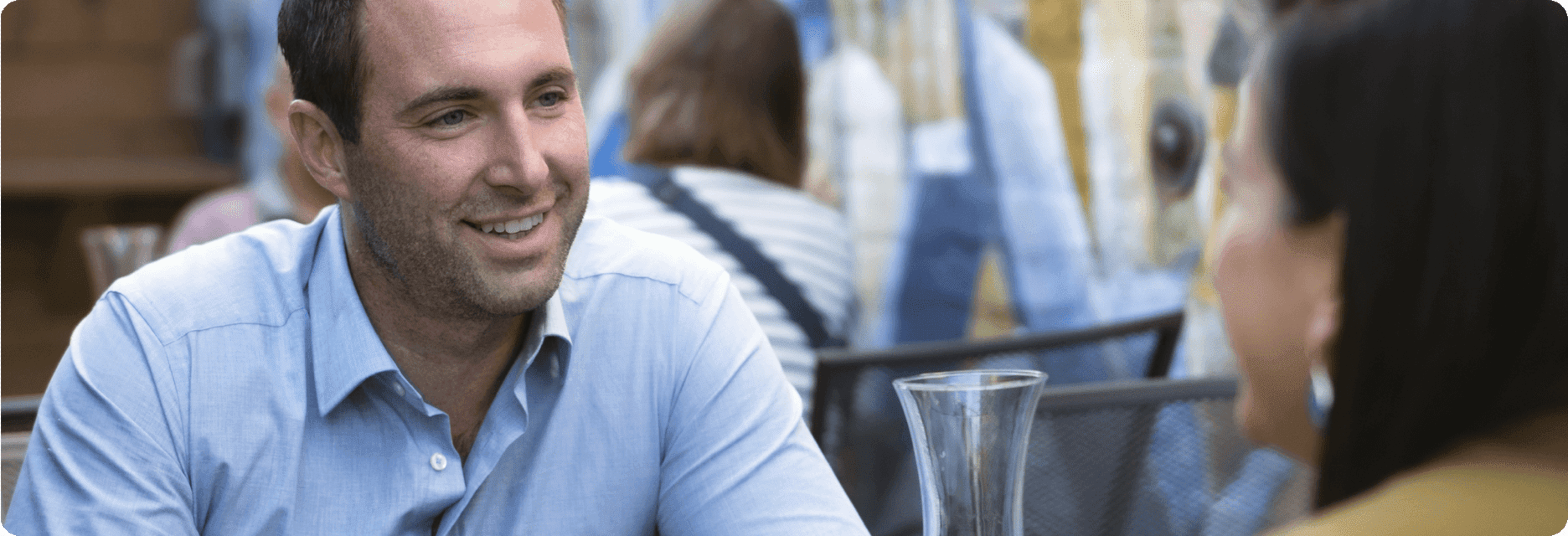 Man smiling while sitting at a table with someone.