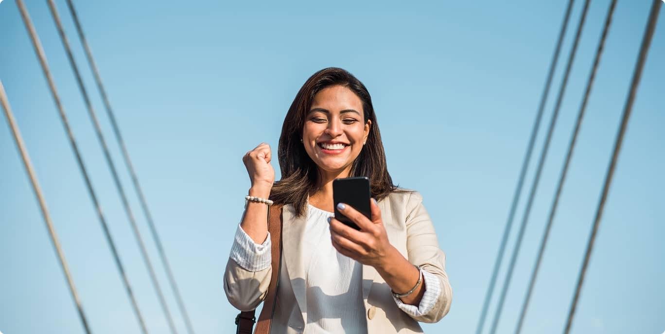 A person excitedly looks at their phone smiling.