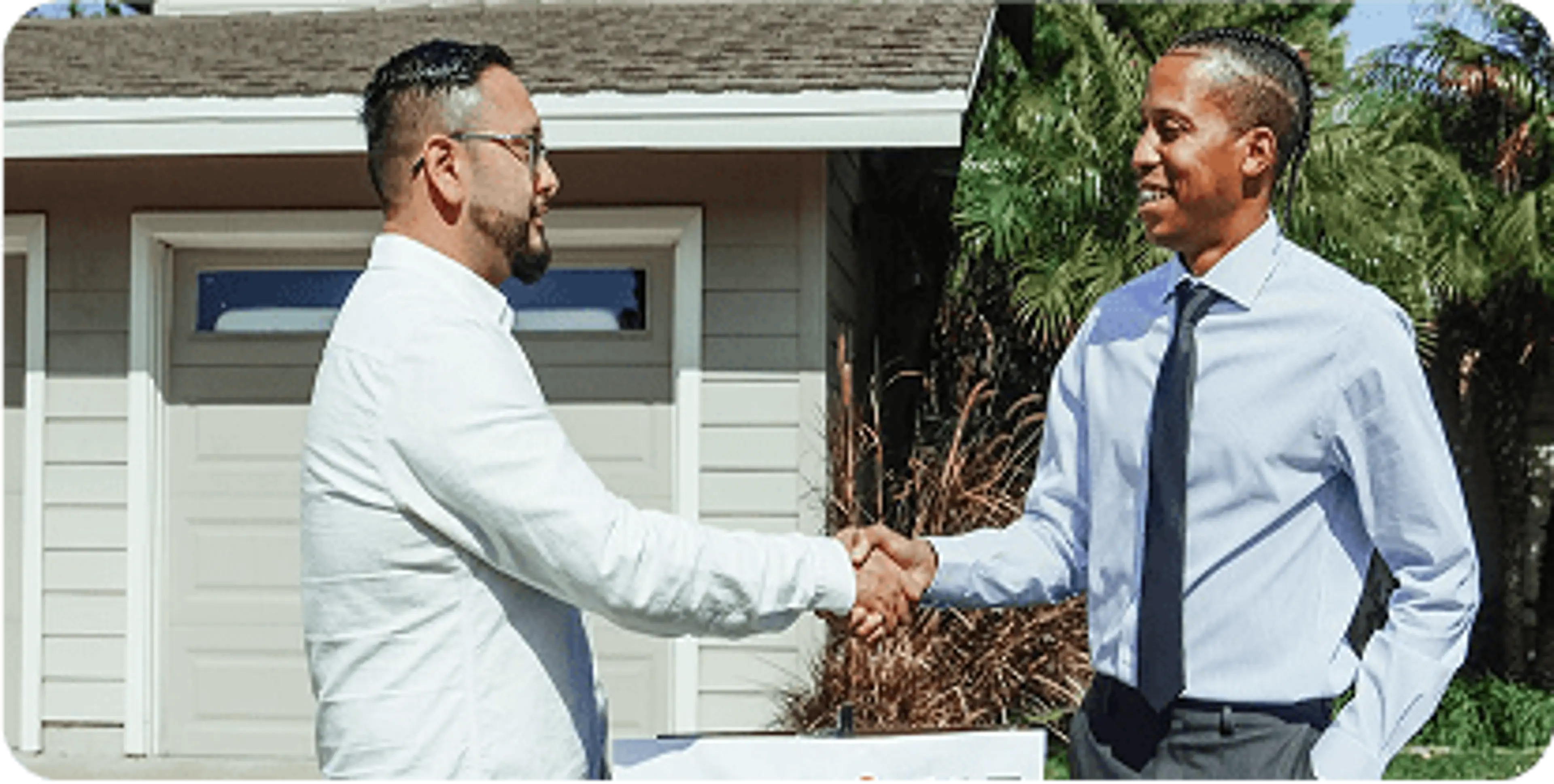 A real estate agent shakes hands with a new homeowner.