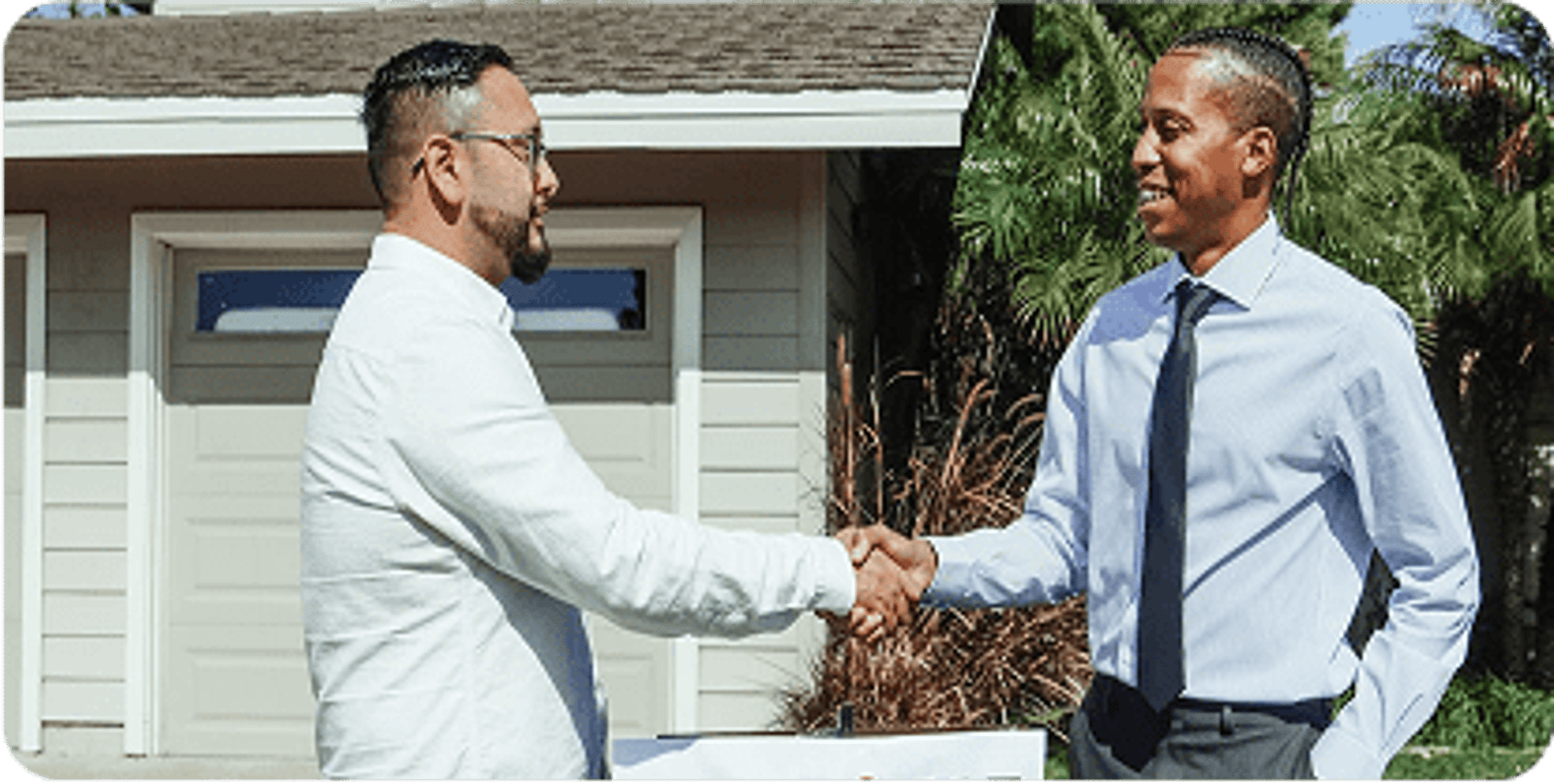 A real estate agent shakes hands with a new homeowner.