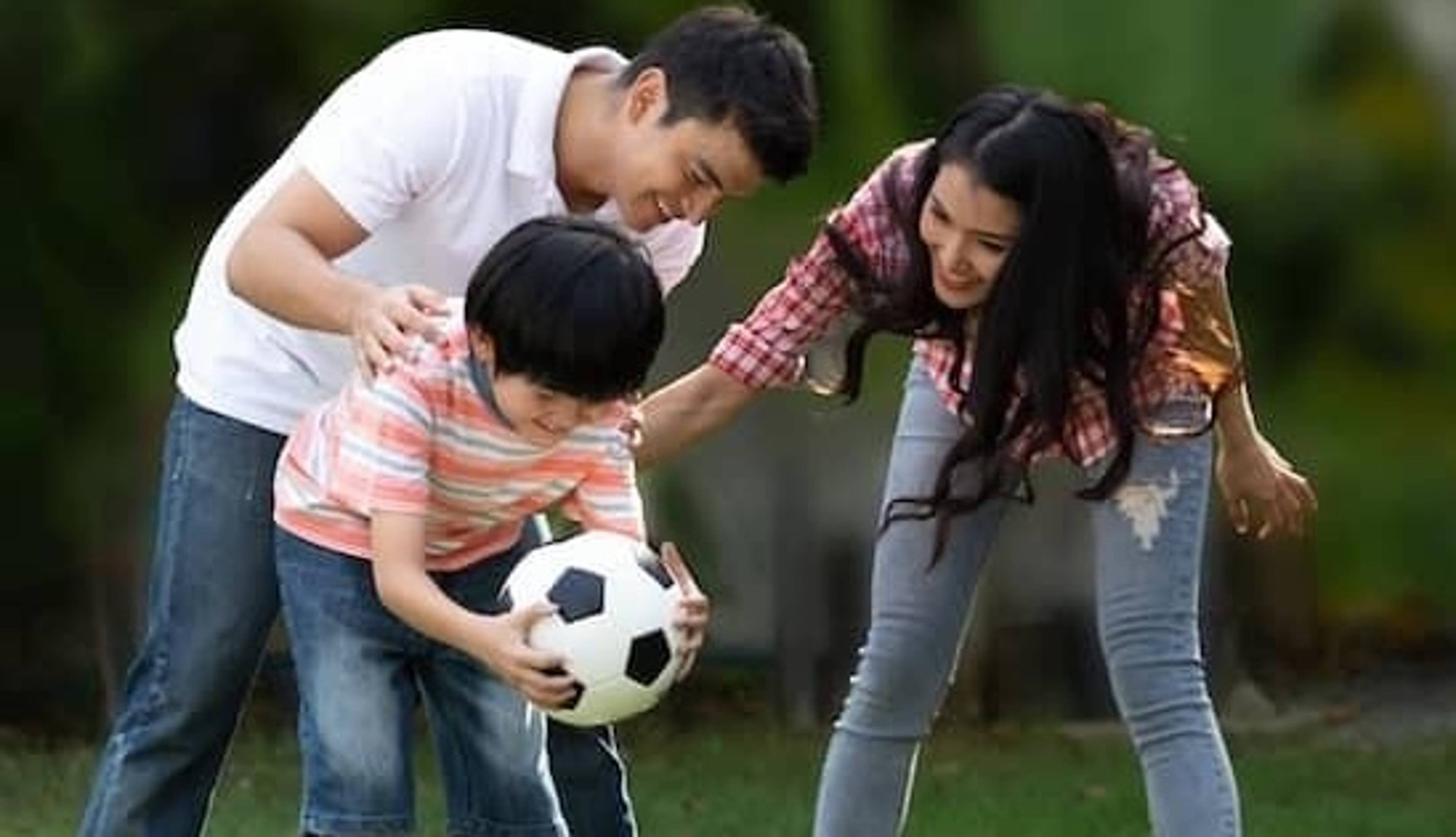 Parents play soccer with their child.