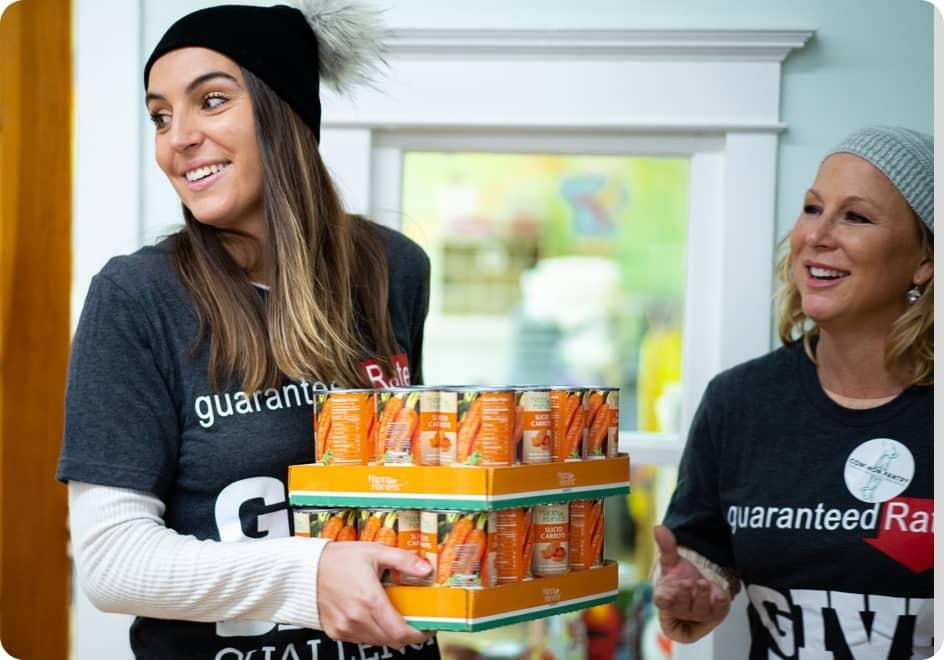 A Rate employee carries boxes of canned goods.