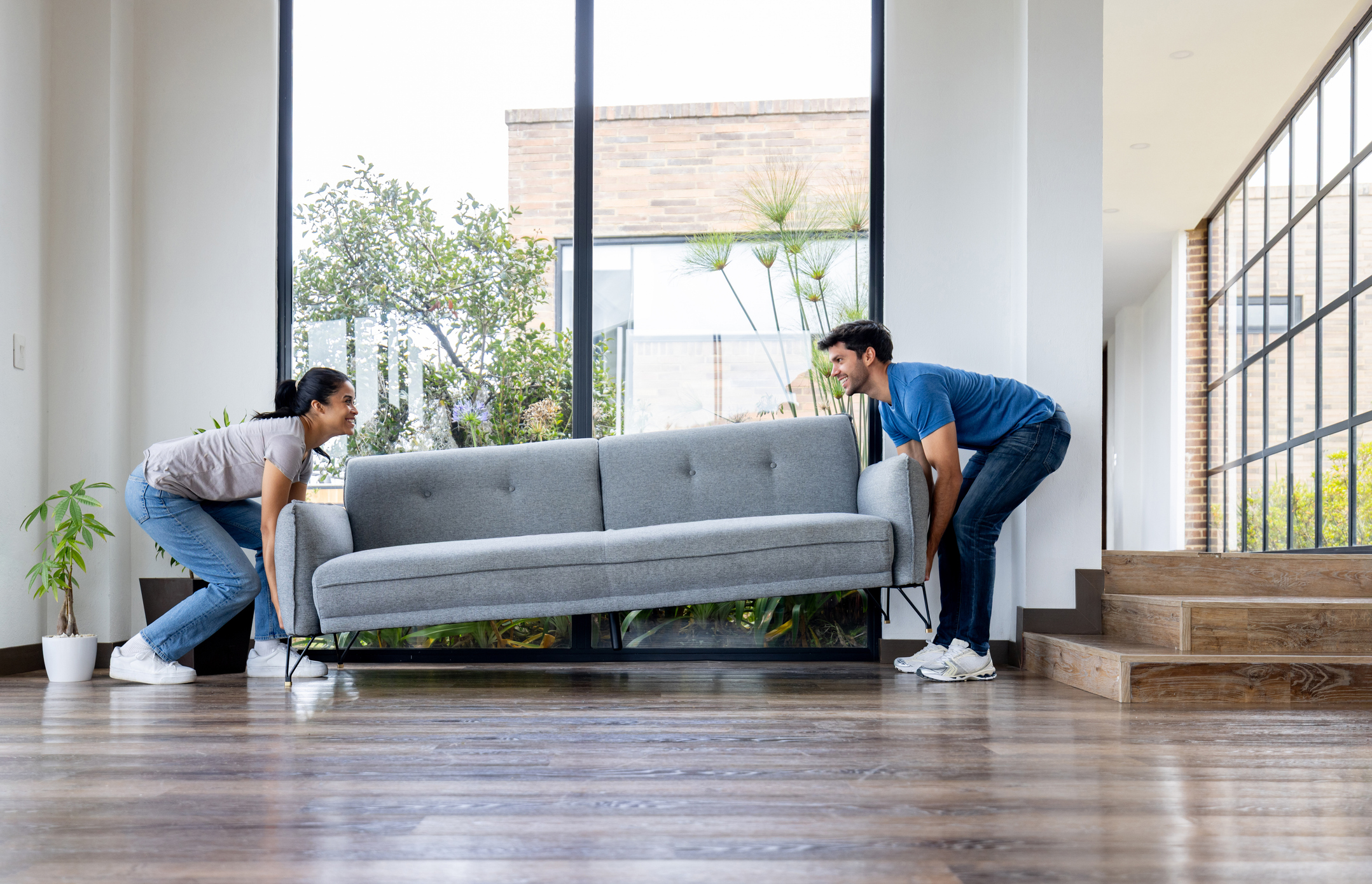 Two people lifting a couch.