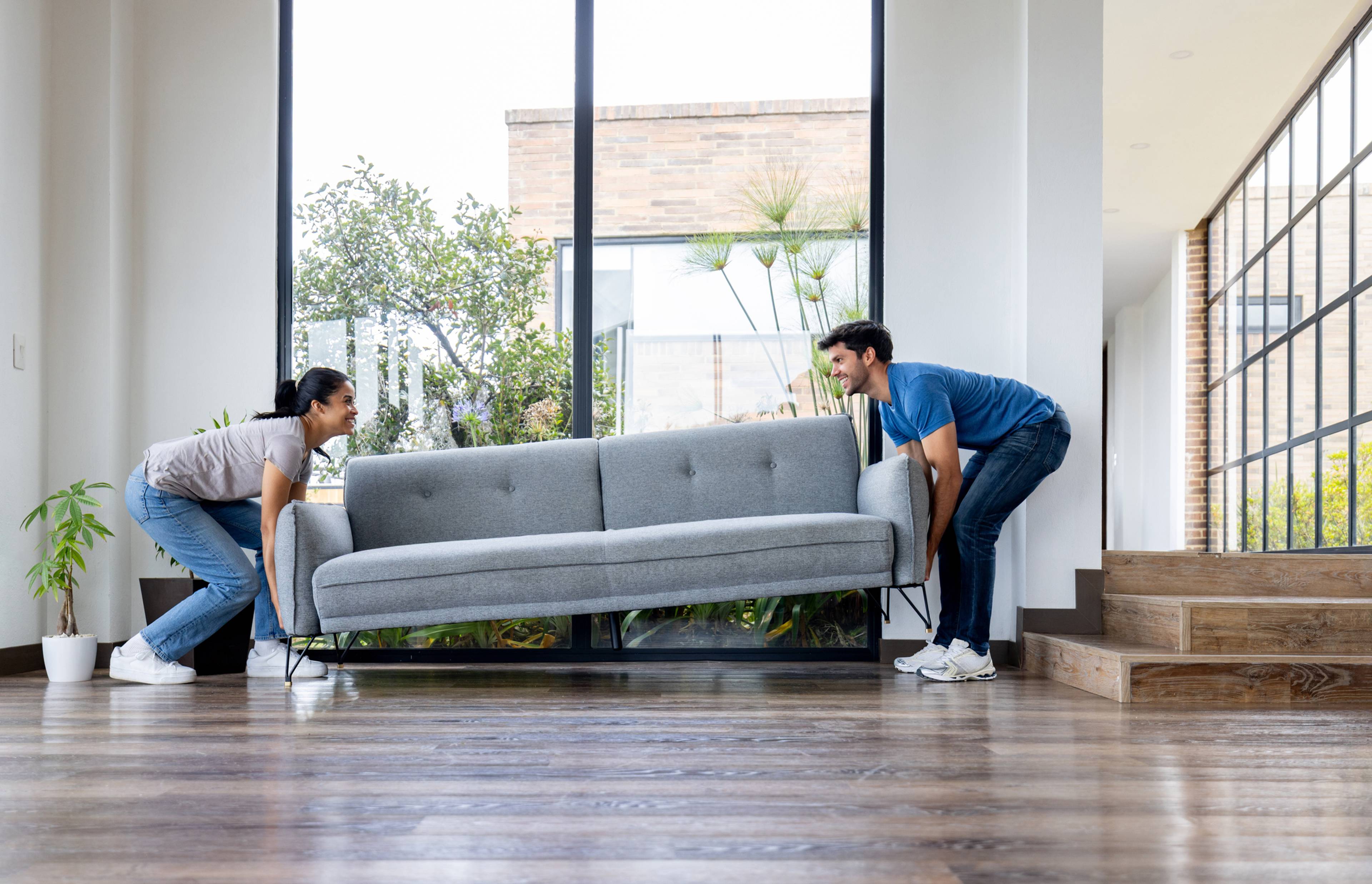 Two people lifting a couch.