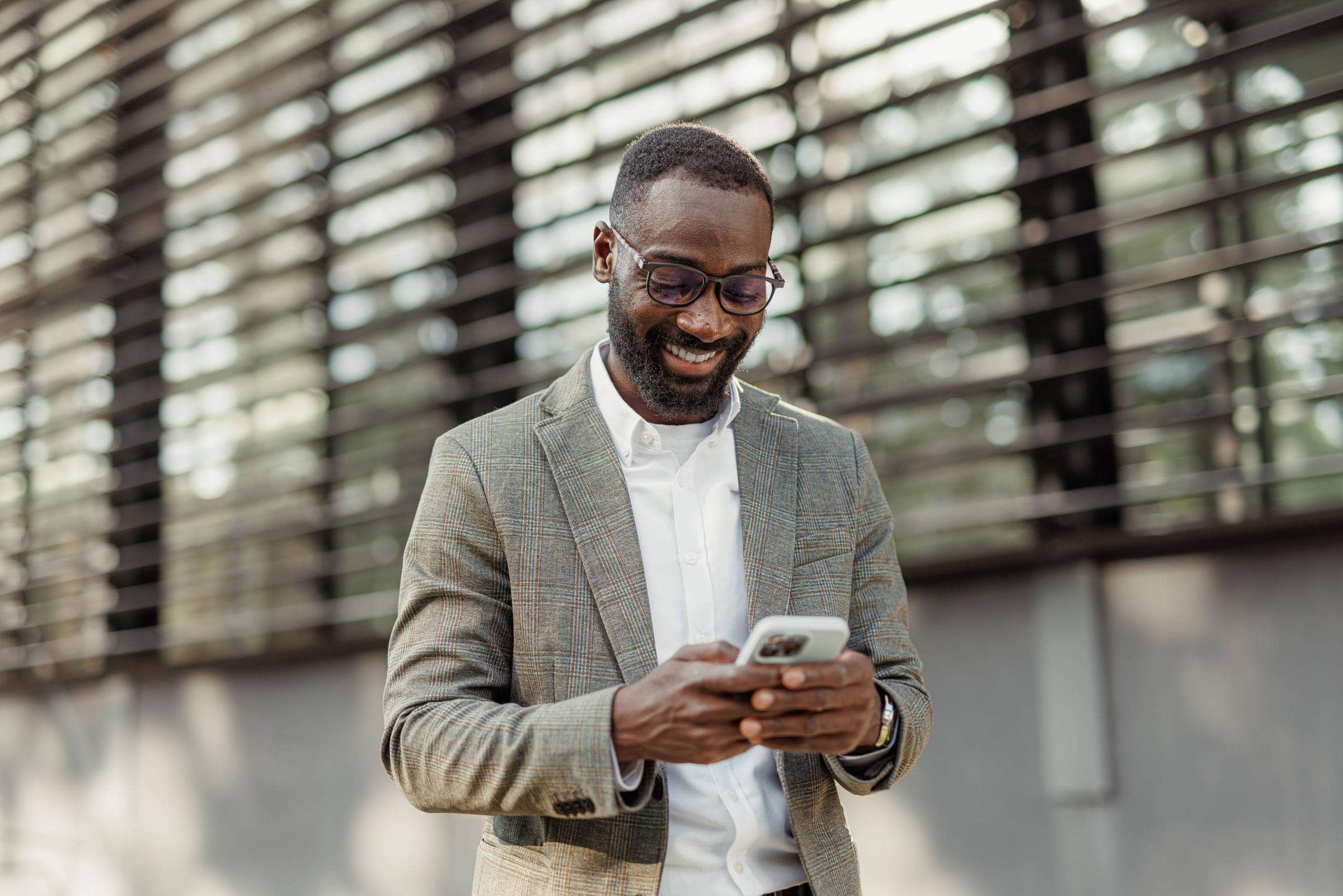 A smiling man looking down at his smartphone