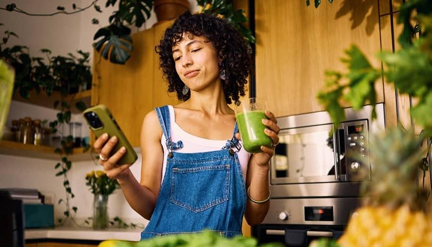 Girl in kitchen with matcha on her cell phone