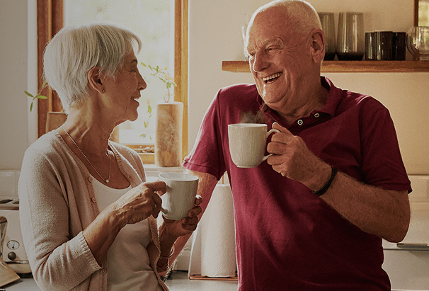 Elderly couple enjoying coffee in their kitchen.