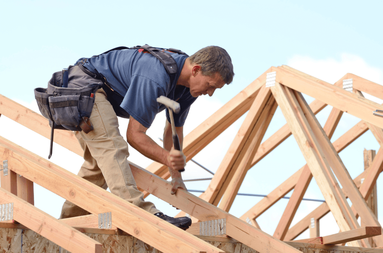 Man building a roof on a new house.