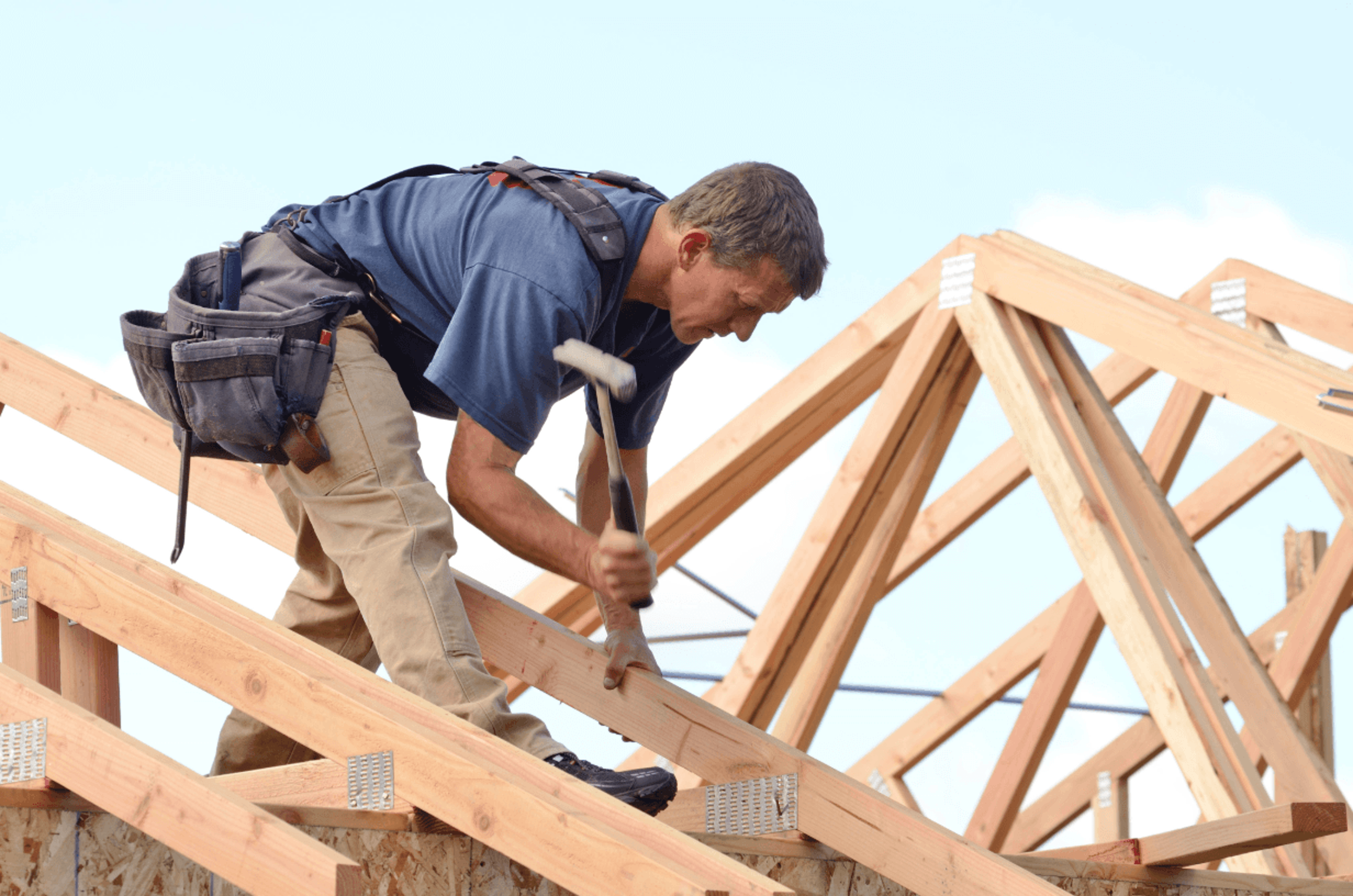 Man building a roof on a new house.