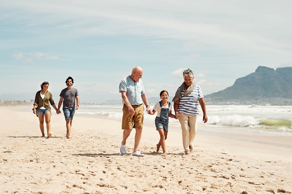 Une fillette à la plage avec ses parents et grands-parents pour un voyage multigénérationnel.