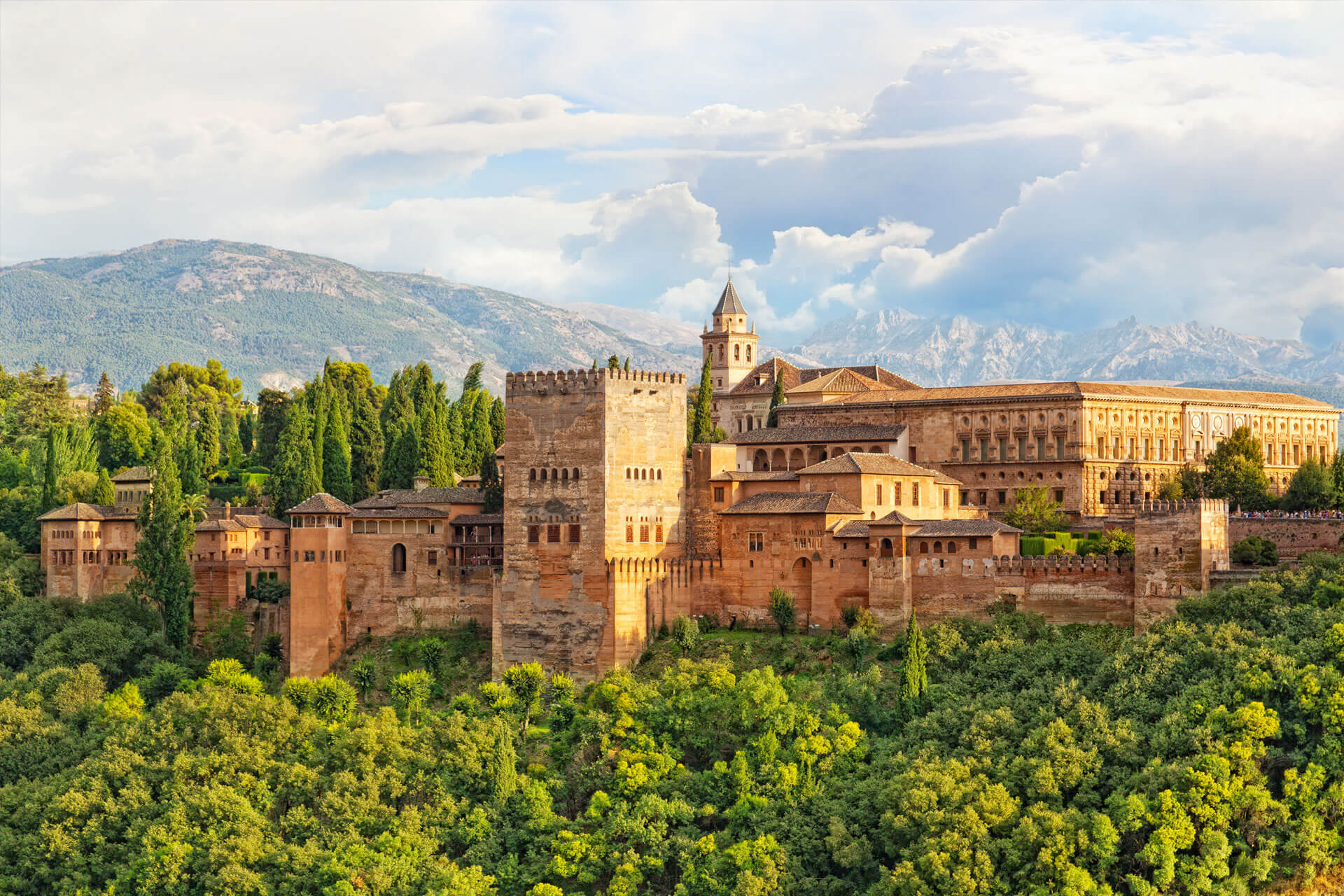 L’Alhambra de Grenade, en Espagne, un palais mauresque de couleur ocre, situé sur une colline et entouré d’une forêt verdoyante.