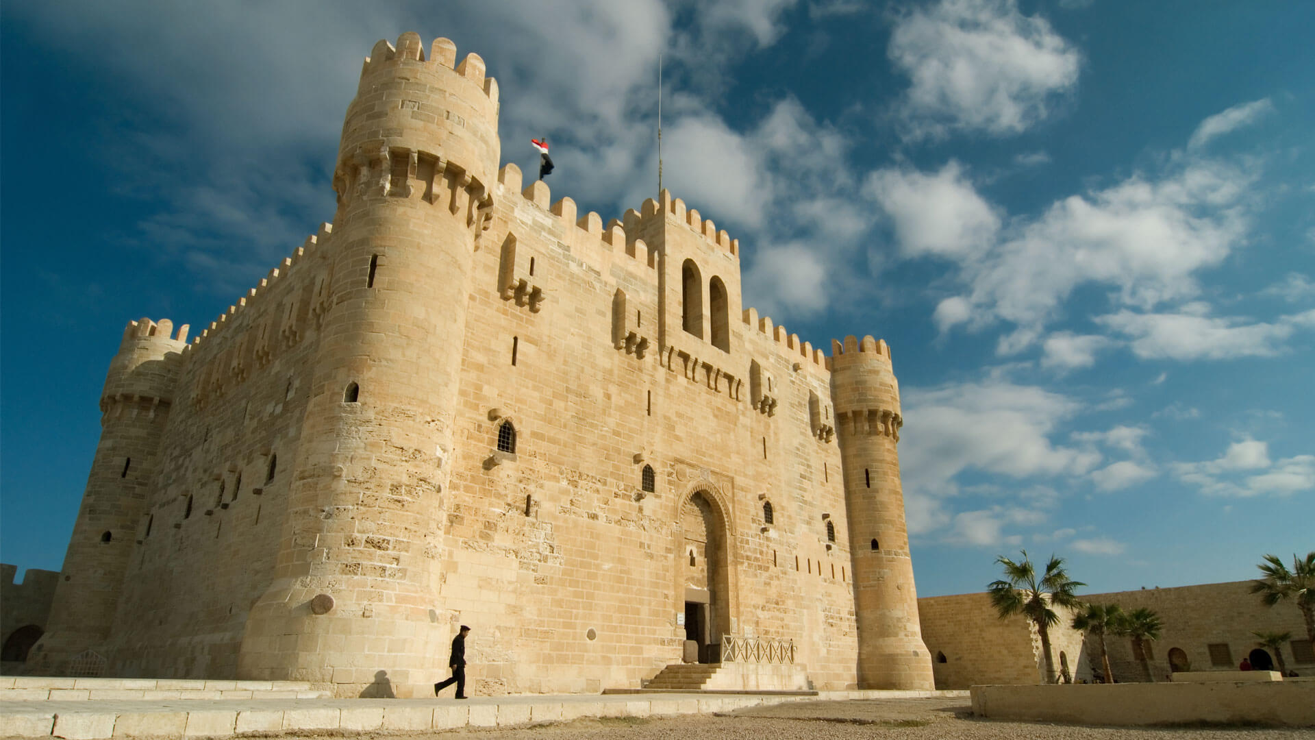 Qaitbay Citadel in Alexandria, Egypt, a medieval stone fortress on the Mediterranean coast under a cloudy sky.