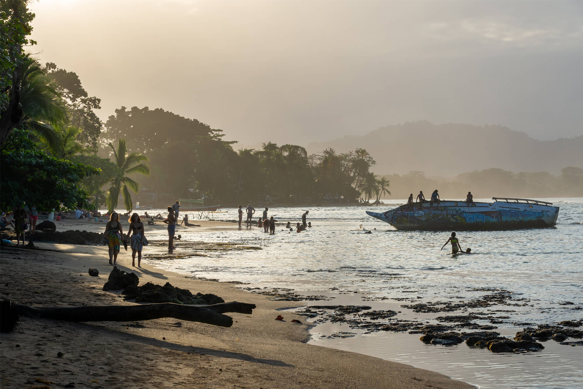  Locals and tourists walking and swimming at sunset on the beach in Puerto Viejo de Talamanca, Costa Rica.