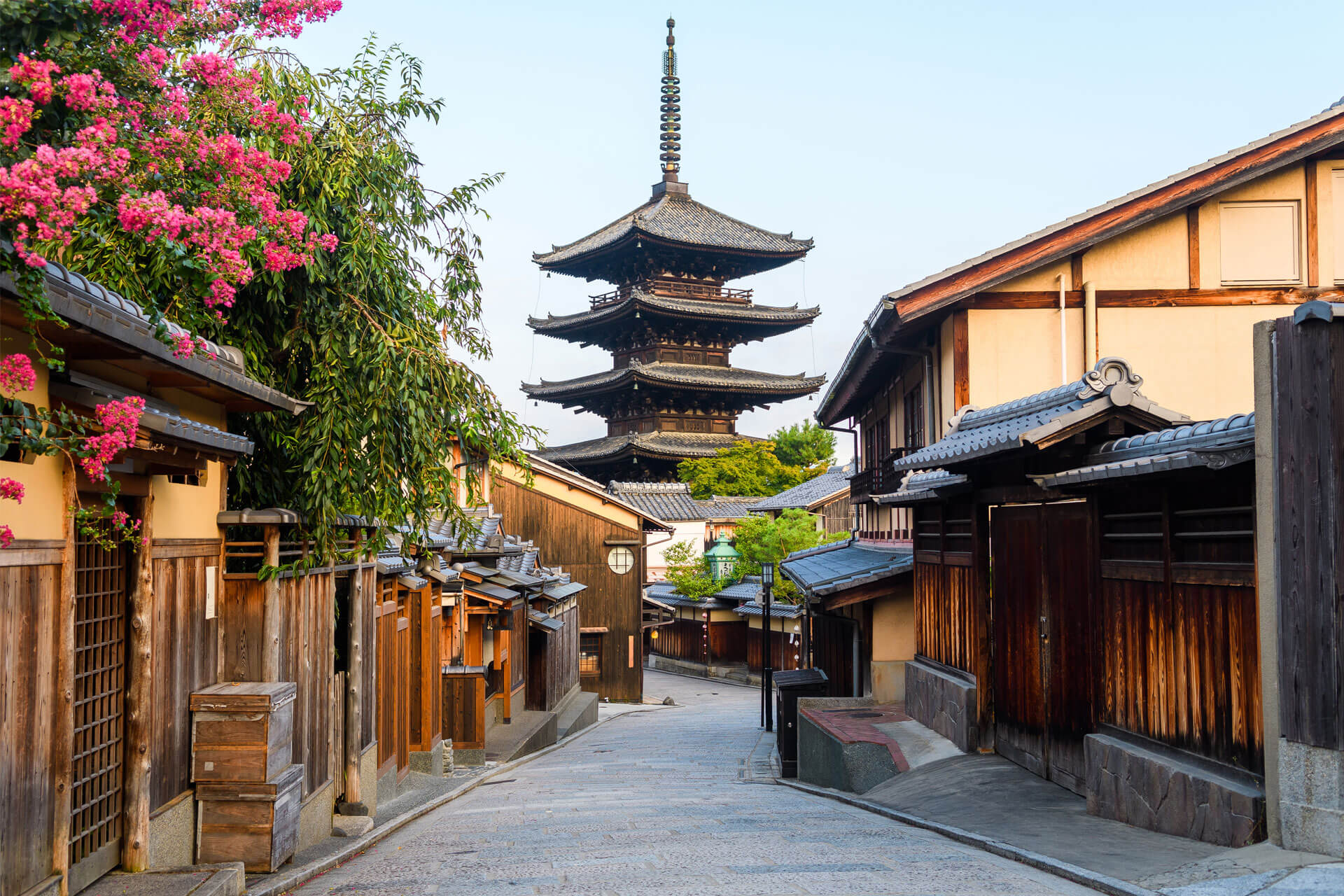 Narrow street of the Higashiyama district of Kyoto, Japan, with wooden houses and the iconic Yasaka Pagoda in the background.