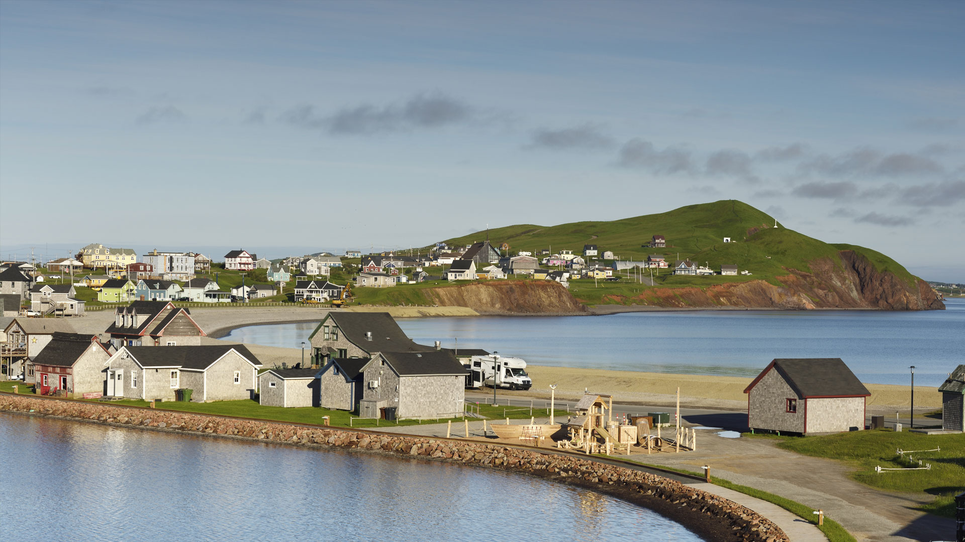 Colourful houses and red sandstone cliffs along the shore in Havre-Aubert, Magdalen Islands.