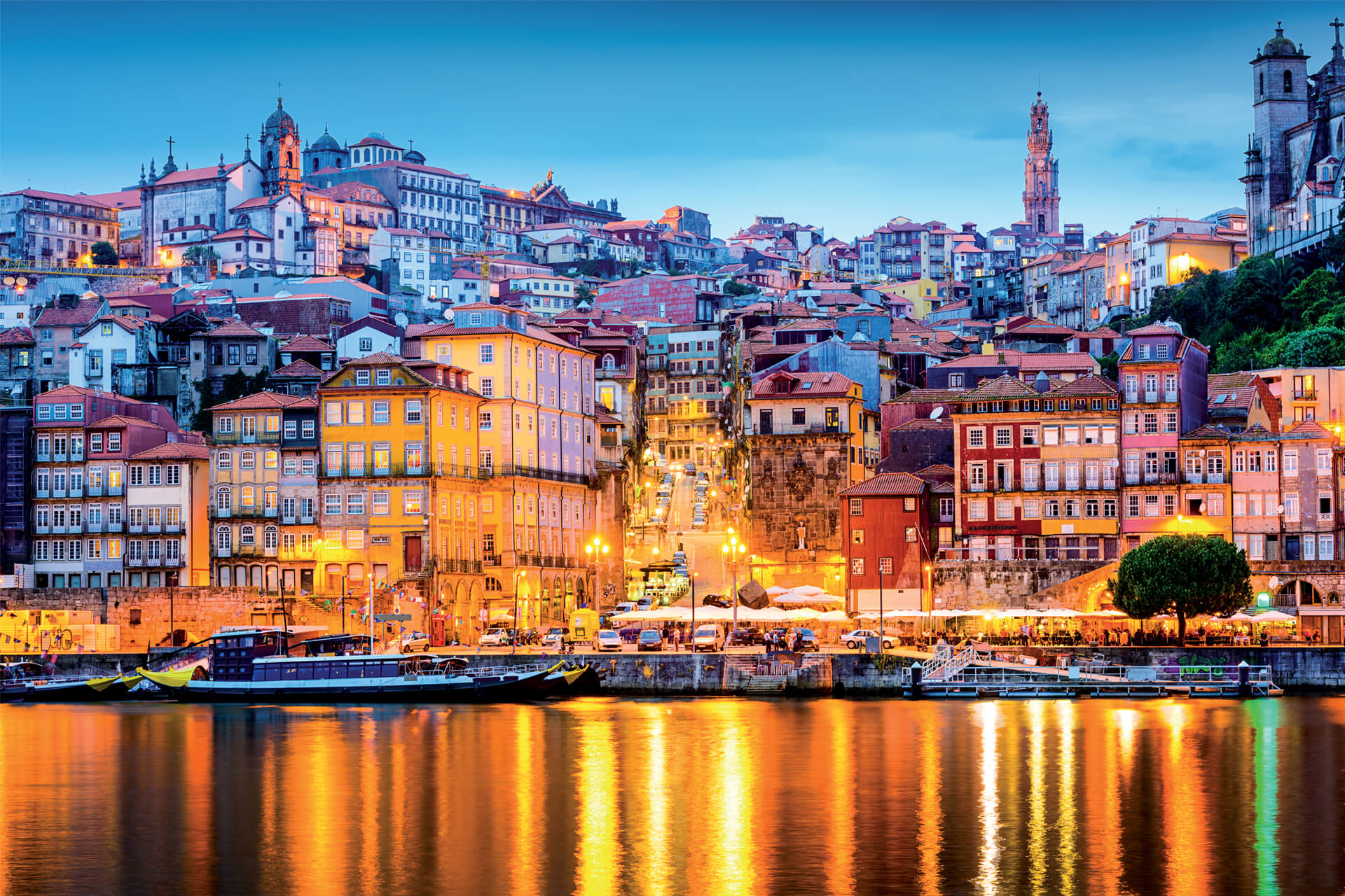 Colourful Ribeira district in Porto, Portugal, illuminated at dusk with reflections shimmering on the Douro River.