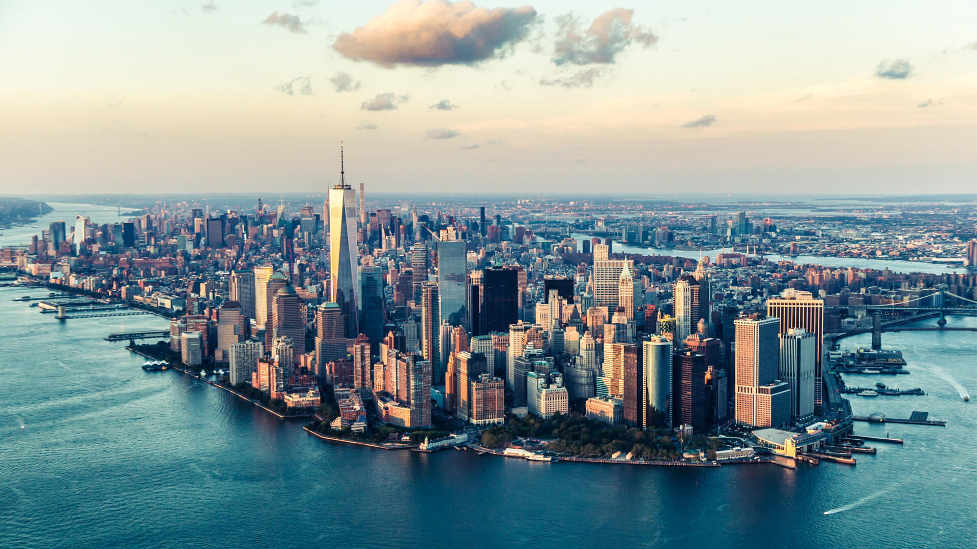 Vue aérienne de Manhattan, New York, avec le One World Trade Center dominant les gratte-ciel et la rivière bordant la ville.