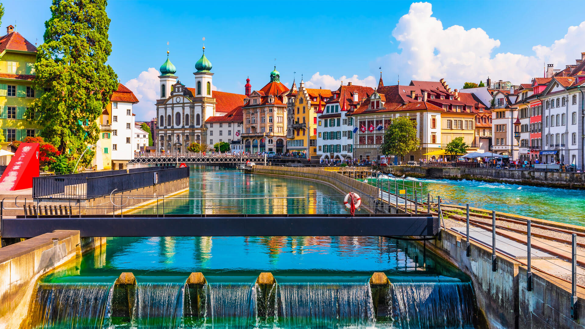 Lucerne en Suisse avec la rivière Reuss, le pont Kapellbrücke, les façades colorées des bâtiments et l’église Saint-Pierre.