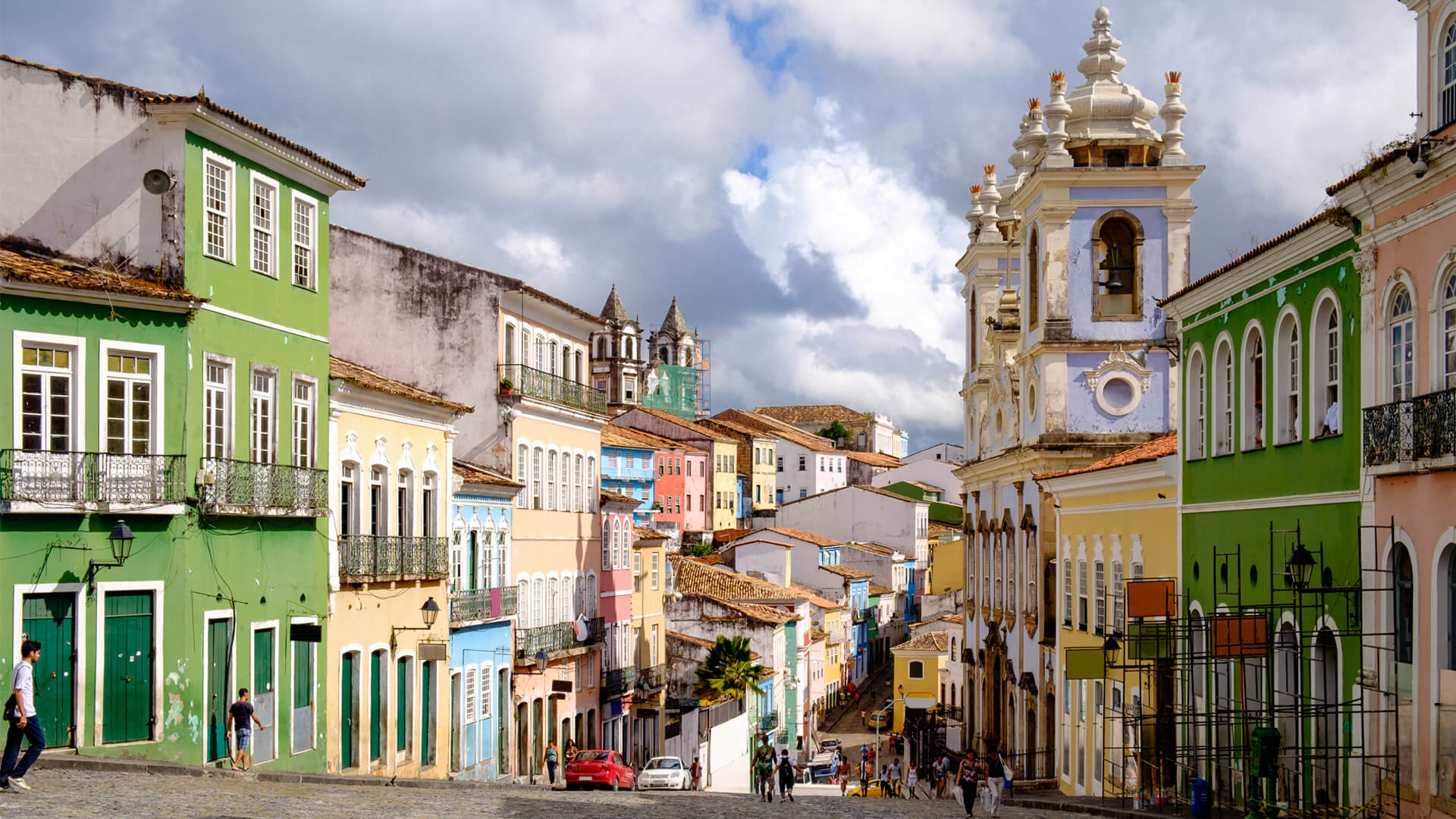 Colourful street in Pelourinho, Salvador de Bahia, Brazil, with baroque church and pastel-coloured houses.