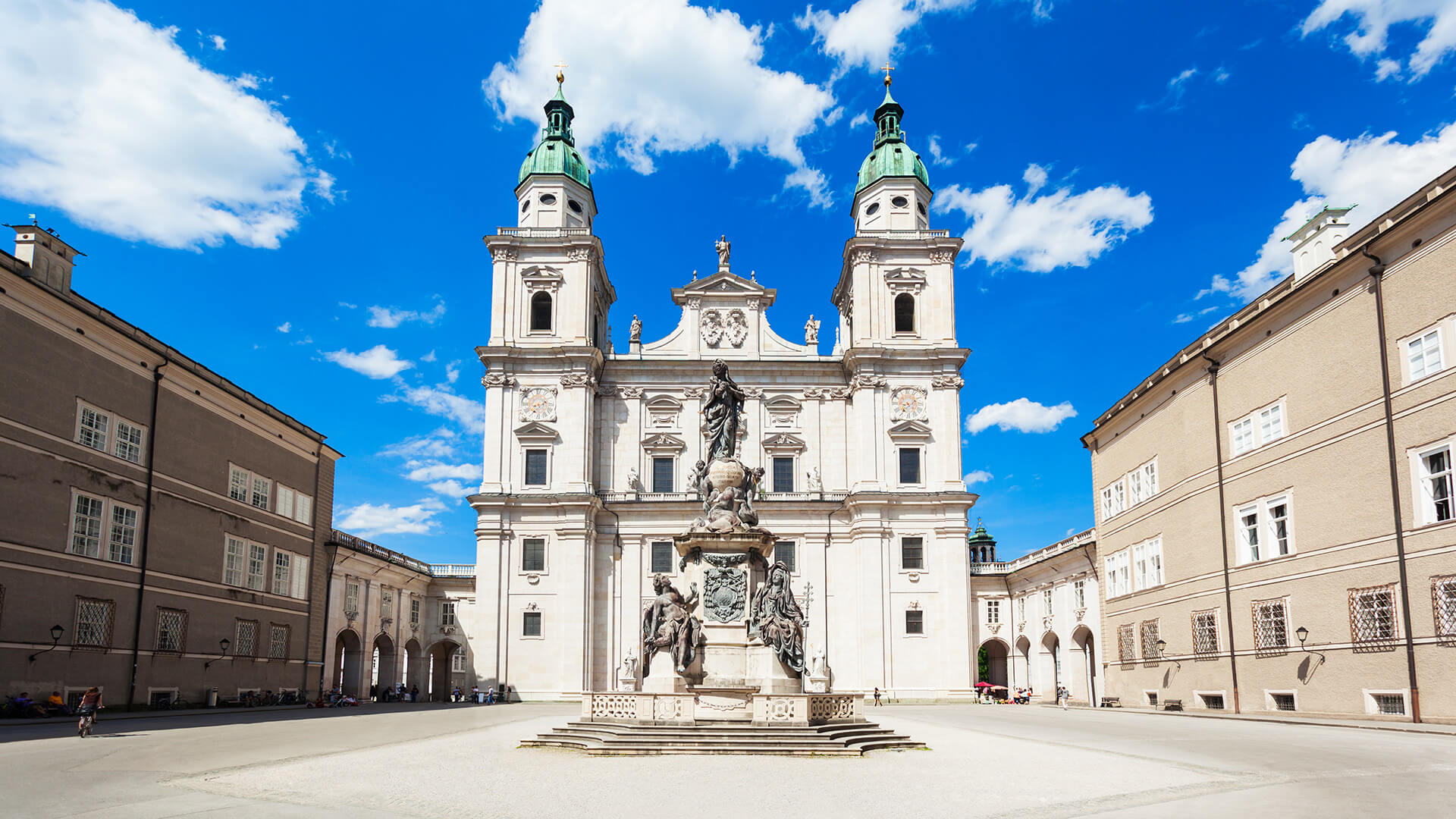 Façade de la cathédrale Saint-Rupert à Salzbourg, en Autriche, sous un ciel bleu, avec une statue au premier plan.