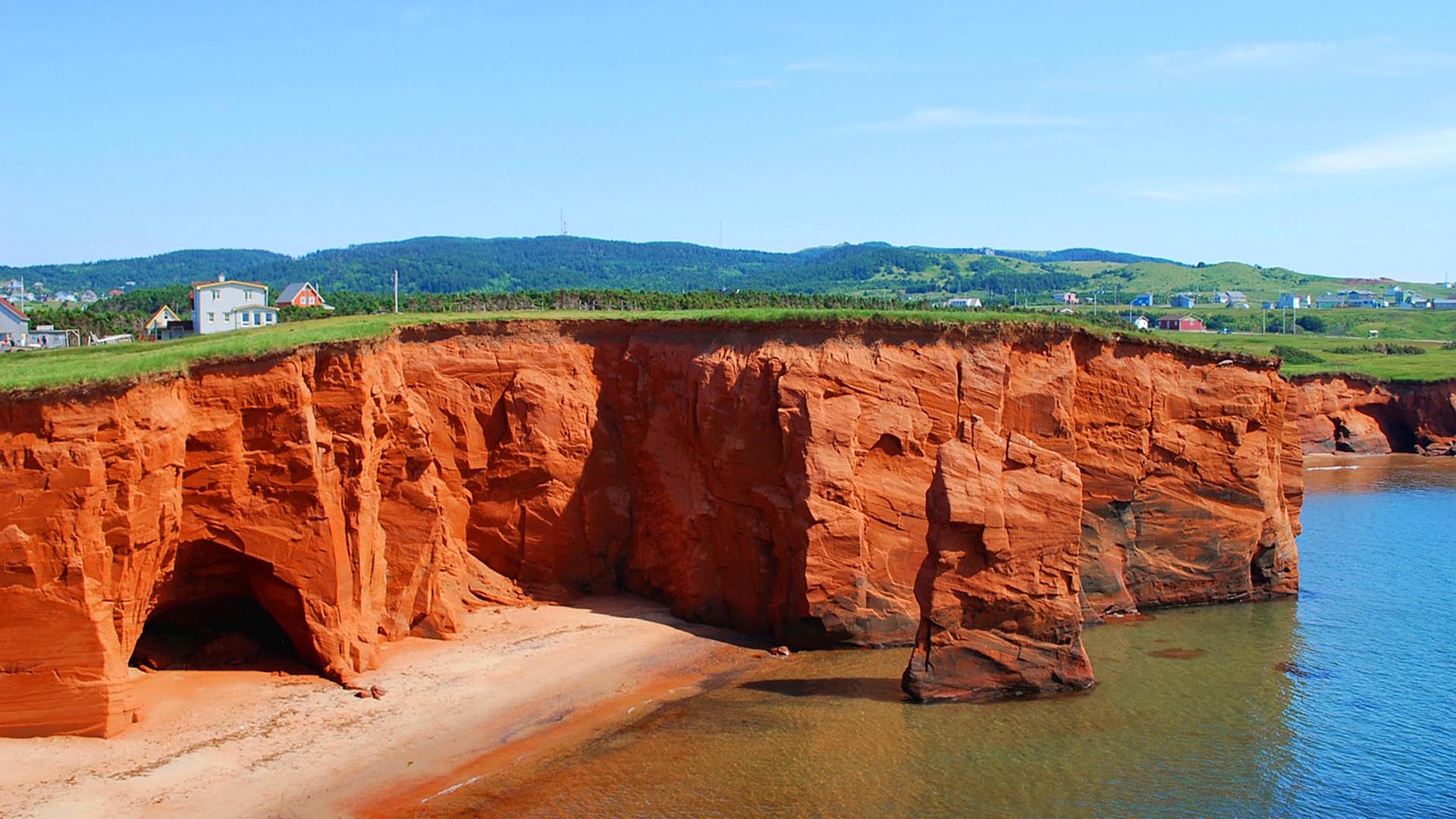 Red sandstone cliffs and sea caves overlooking a beach in the Magdalen Islands along the Gulf of St. Lawrence.