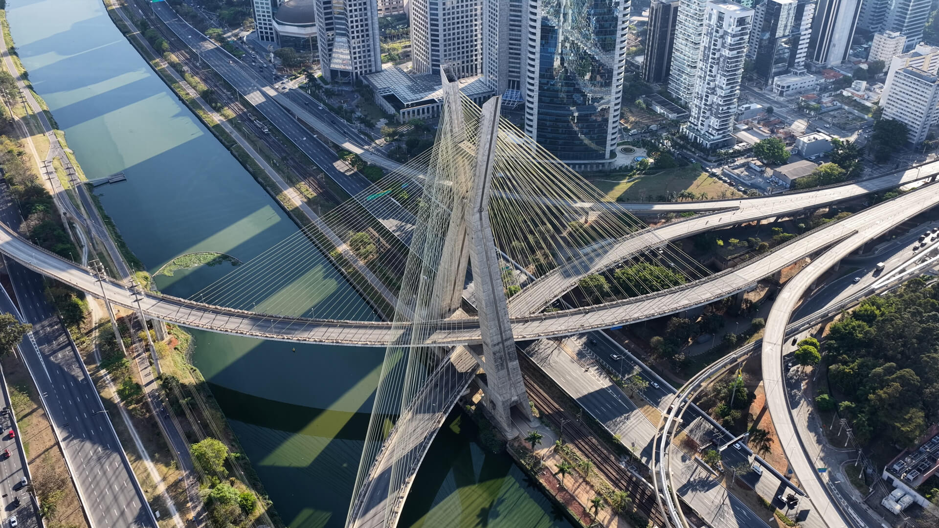 Aerial view of the Octávio Frias de Oliveira bridge in São Paulo, Brazil, surrounded by highways and skyscrapers.