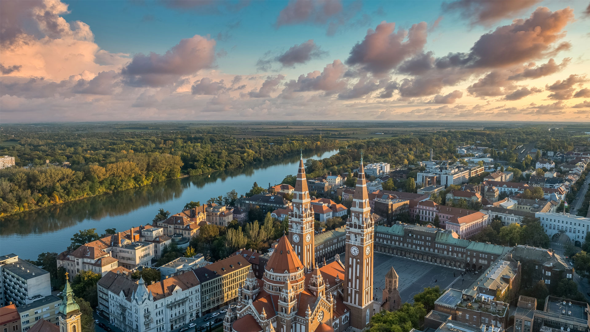 Vue aérienne de Szeged en Hongrie avec la Cathédrale votive au centre et la rivière Tisza entourée d’une végétation dense.