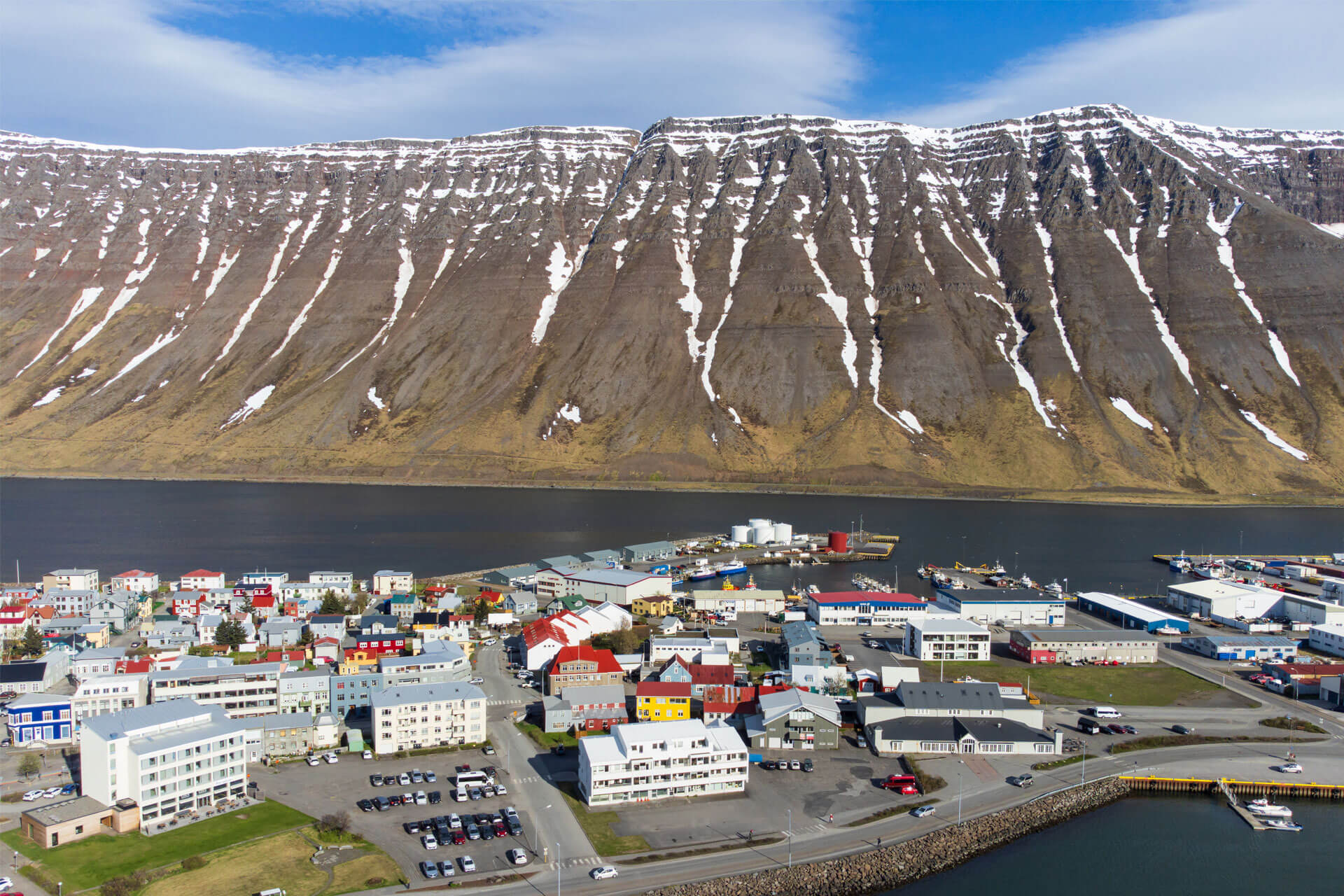Aerial view of Ísafjörður, a small town in Iceland with colourful houses, surrounded by steep mountains and fjords.