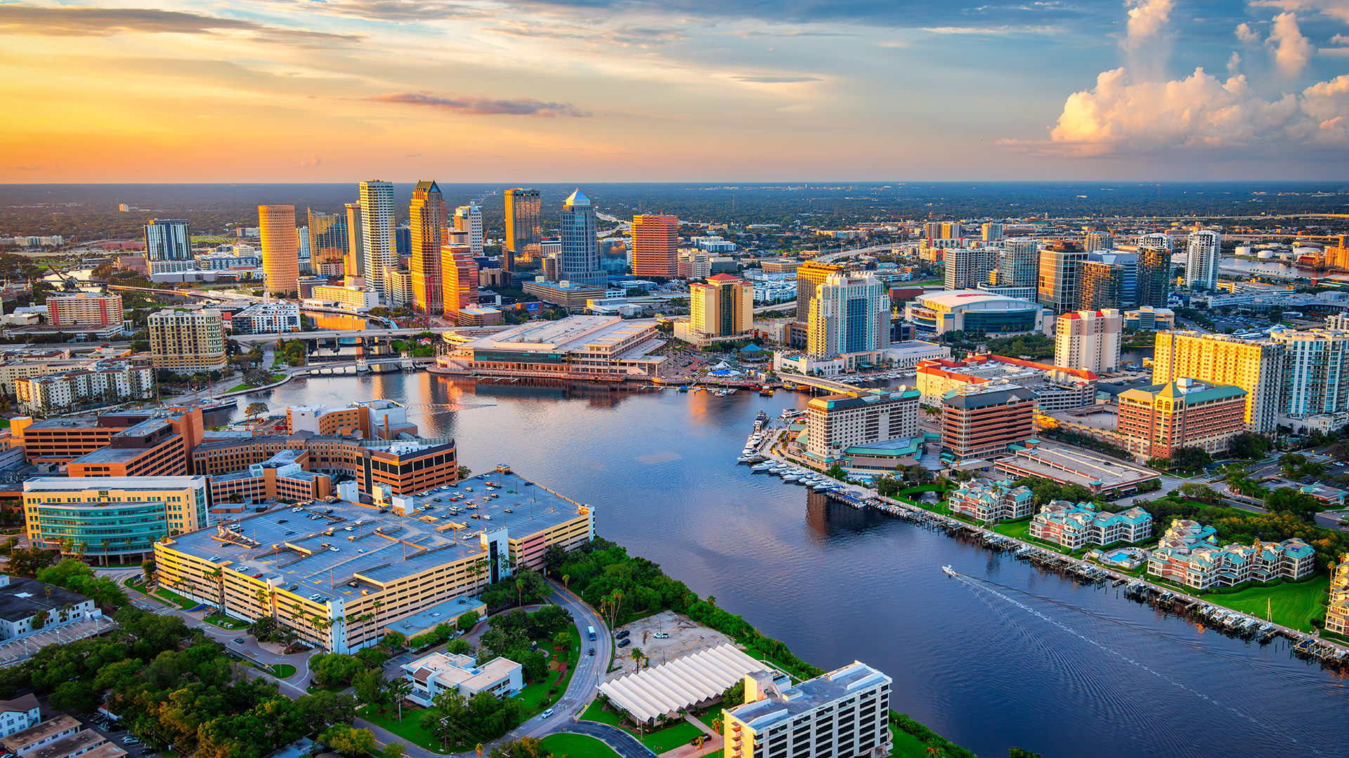 Aerial view of Tampa, Florida, at sunset with skyscrapers and the Hillsborough River running through the city.