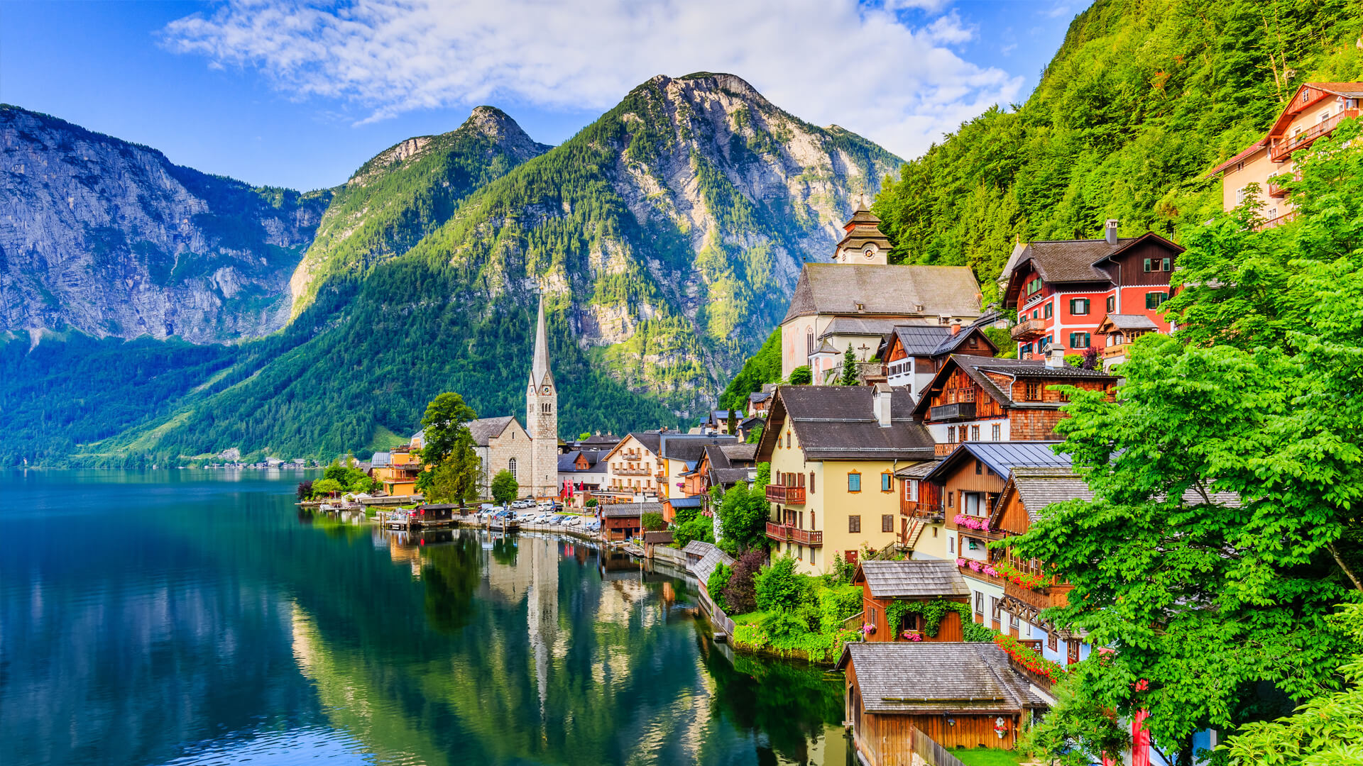 Village pittoresque de Hallstatt, en Autriche, avec maisons colorées et église au bord du lac, entouré de montagnes alpines.