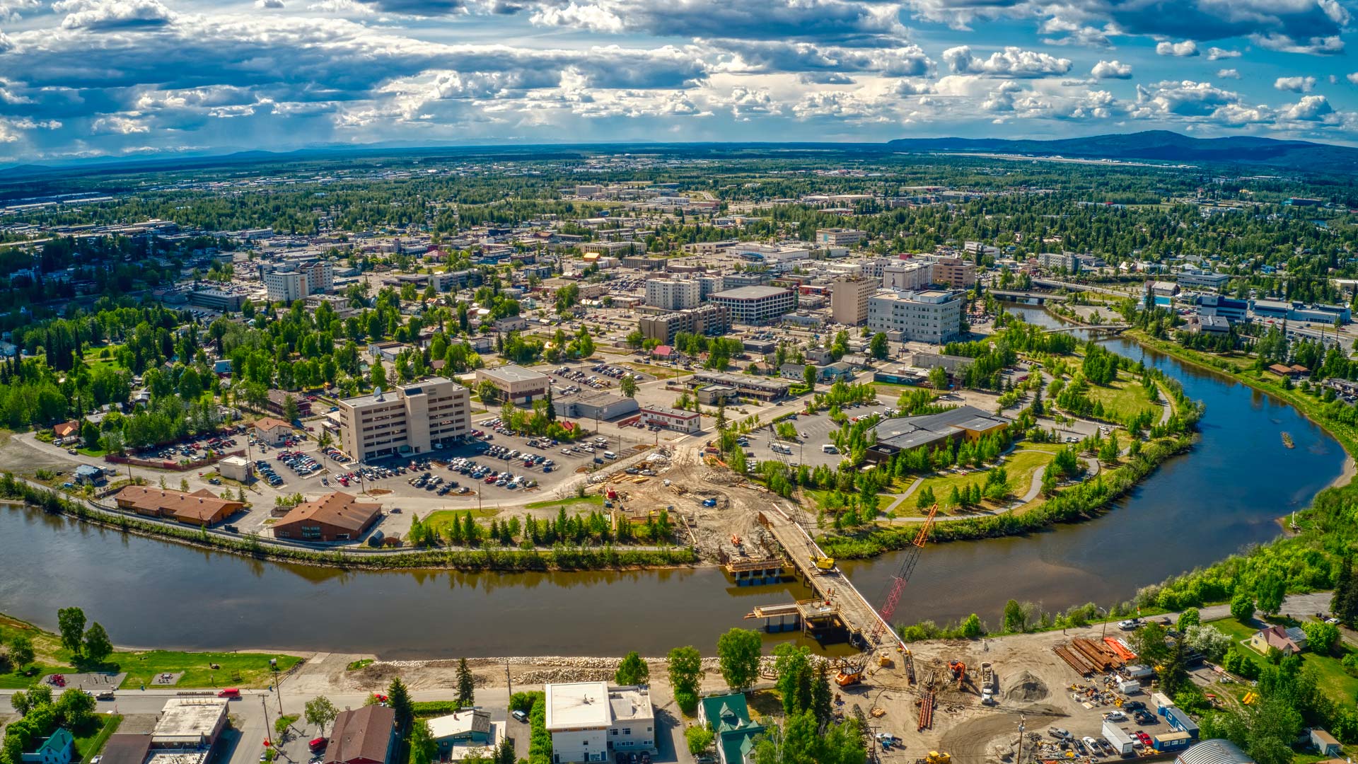 Vue aérienne de la ville de Fairbanks en Alaska, en été, traversée par la rivière Chena qui serpente le paysage urbain.