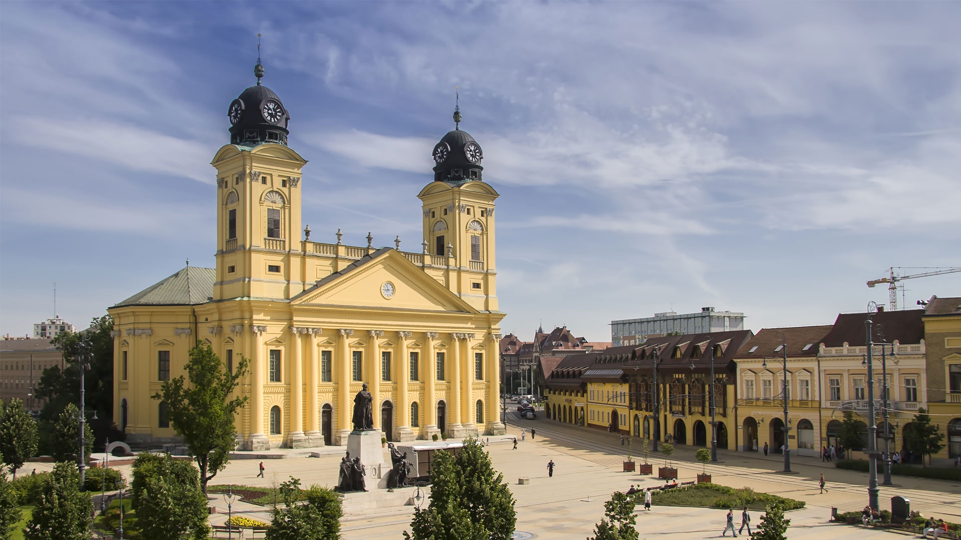 Grande Église réformée de Debrecen en Hongrie, vue en plein jour sur la place Kossuth avec arbres et centre-ville historique.