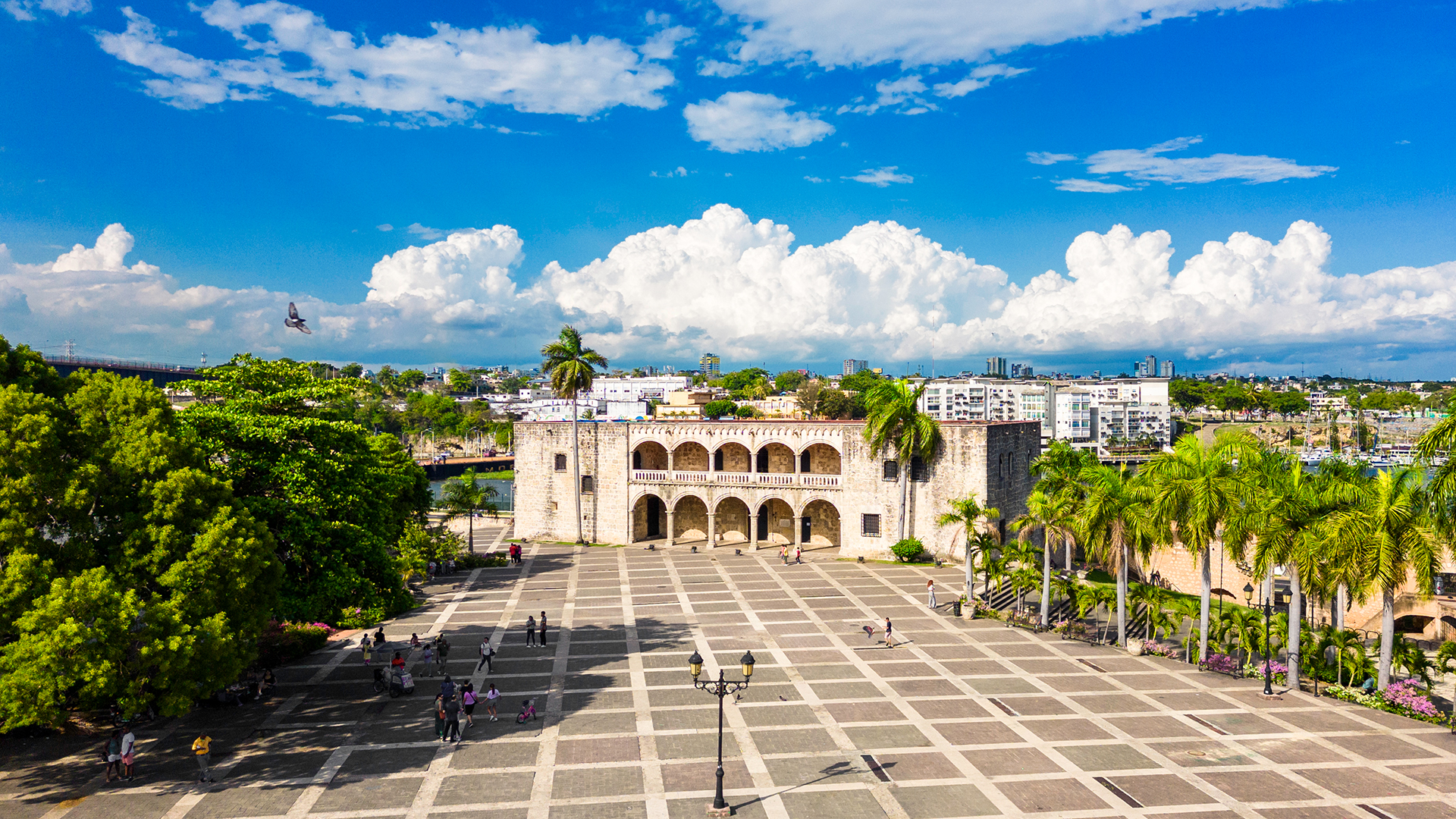 Panoramic view of the Alcázar de Colón in Santo Domingo, Dominican Republic, surrounded by palm trees.