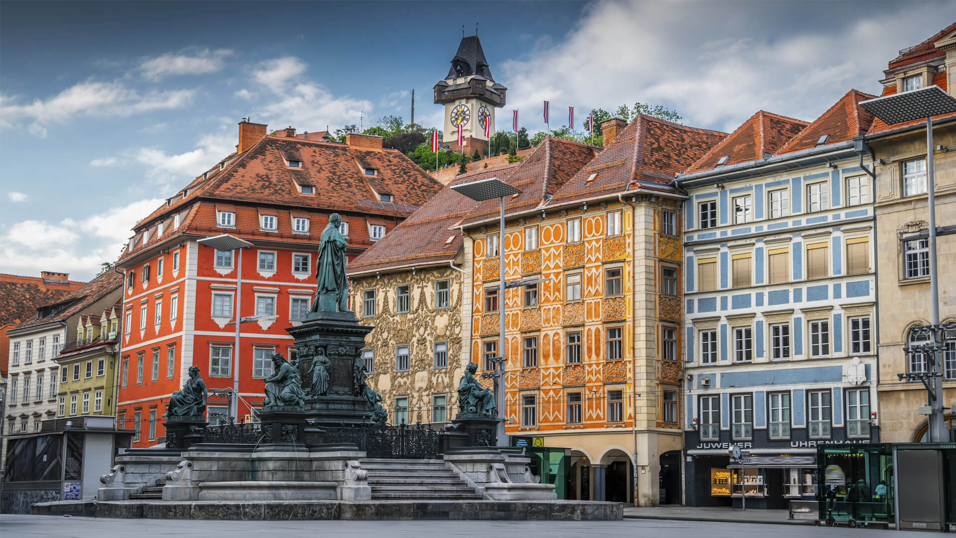 Hauptplatz, place centrale de Graz, en Autriche, ses bâtiments historiques colorés, sa fontaine et la tour de l’Horloge.