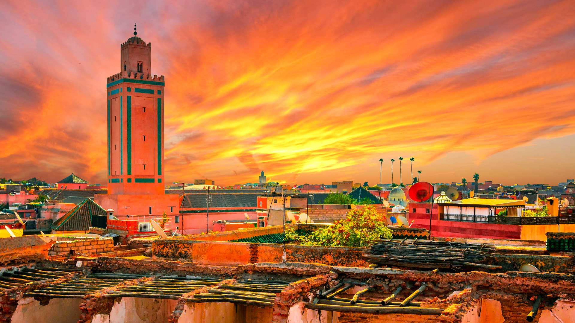 Superbe coucher de soleil aux teintes orangées sur la médina de Marrakech, au Maroc, avec le minaret d'une mosquée visible au loin.