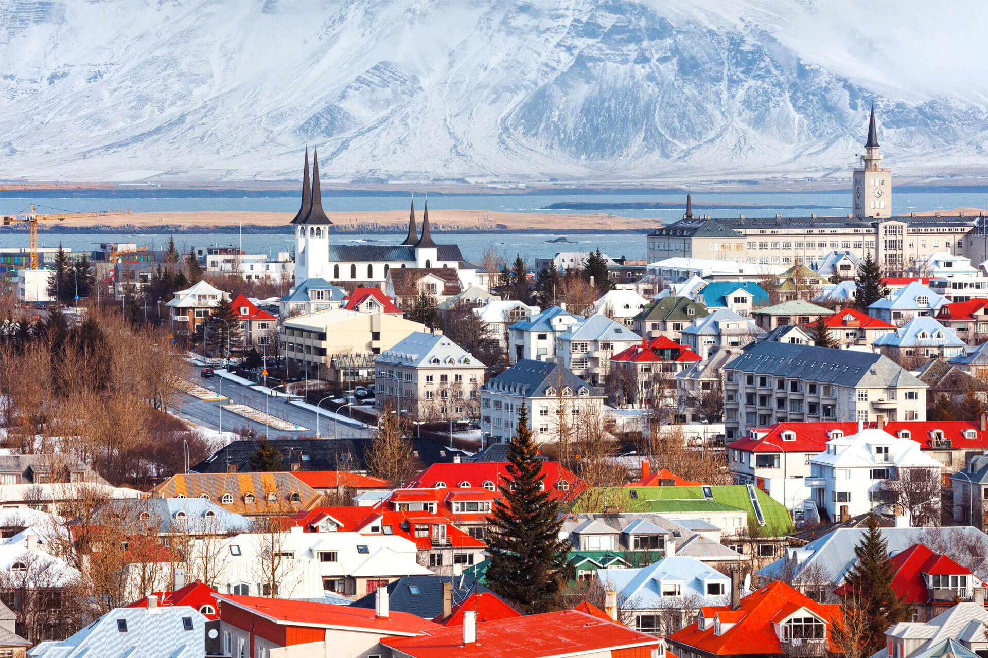 Aerial view of Reykjavik, Iceland’s capital, with colourful rooftops and snow-covered Mount Esja in the background.