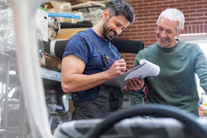 Two workers smiling and discussing over a piece of paper