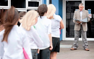 Teacher taking attendance outside of a school during a fire drill