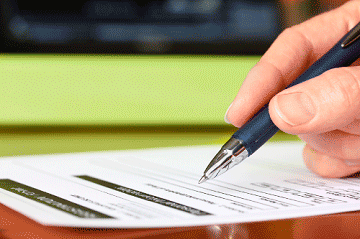 Hand holding a pen and filling out a paper form