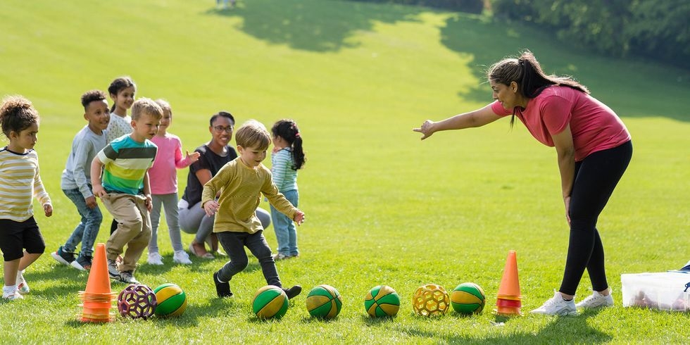 coach teaching kids how to play soccer