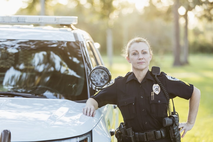 Female police officer stands by cruiser