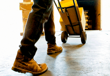 Someone wearing work boots loading a semi truck