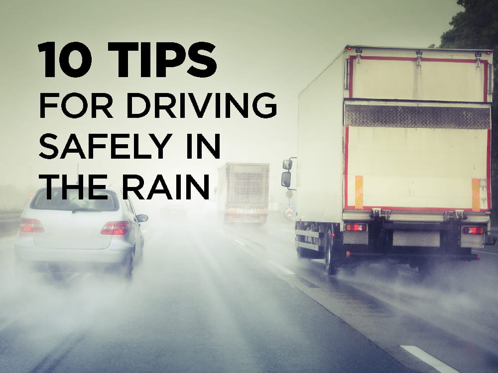 Multiple vehicles driving in the rain spraying water up behind them.