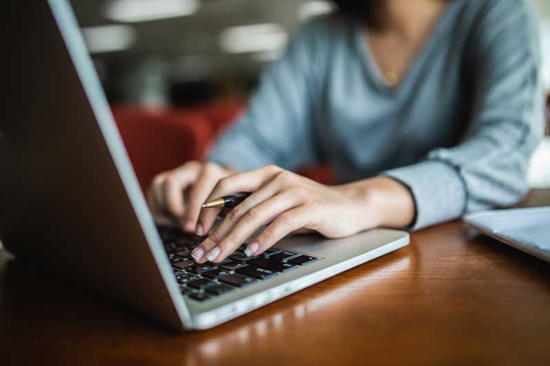 Women in blue shirt working at laptop.