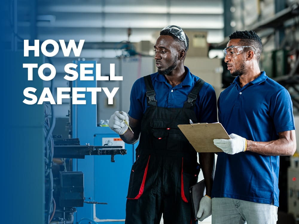 Two men in a warehouse, one with a clipboard, discussing something in regards to a machine