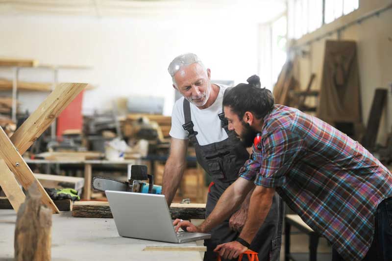 A couple tradesman at a laptop having a discussion