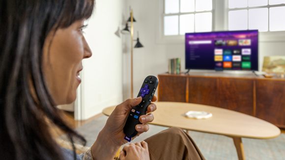 Person using the Roku Voice Remote with the Roku Streaming Stick Plus to control their TV