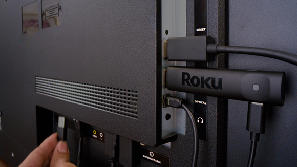 The Roku Streaming Stick Plus plugged into a port in the back of a TV
