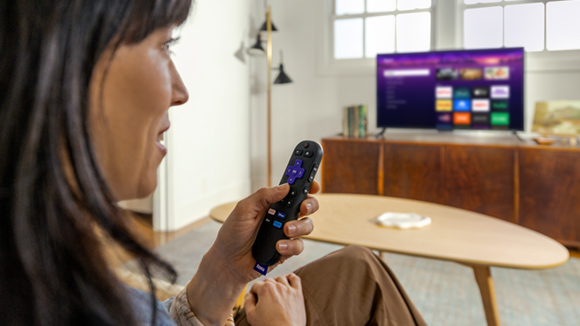 Person using the Roku Voice Remote with the Roku Streaming Stick Plus to control their TV
