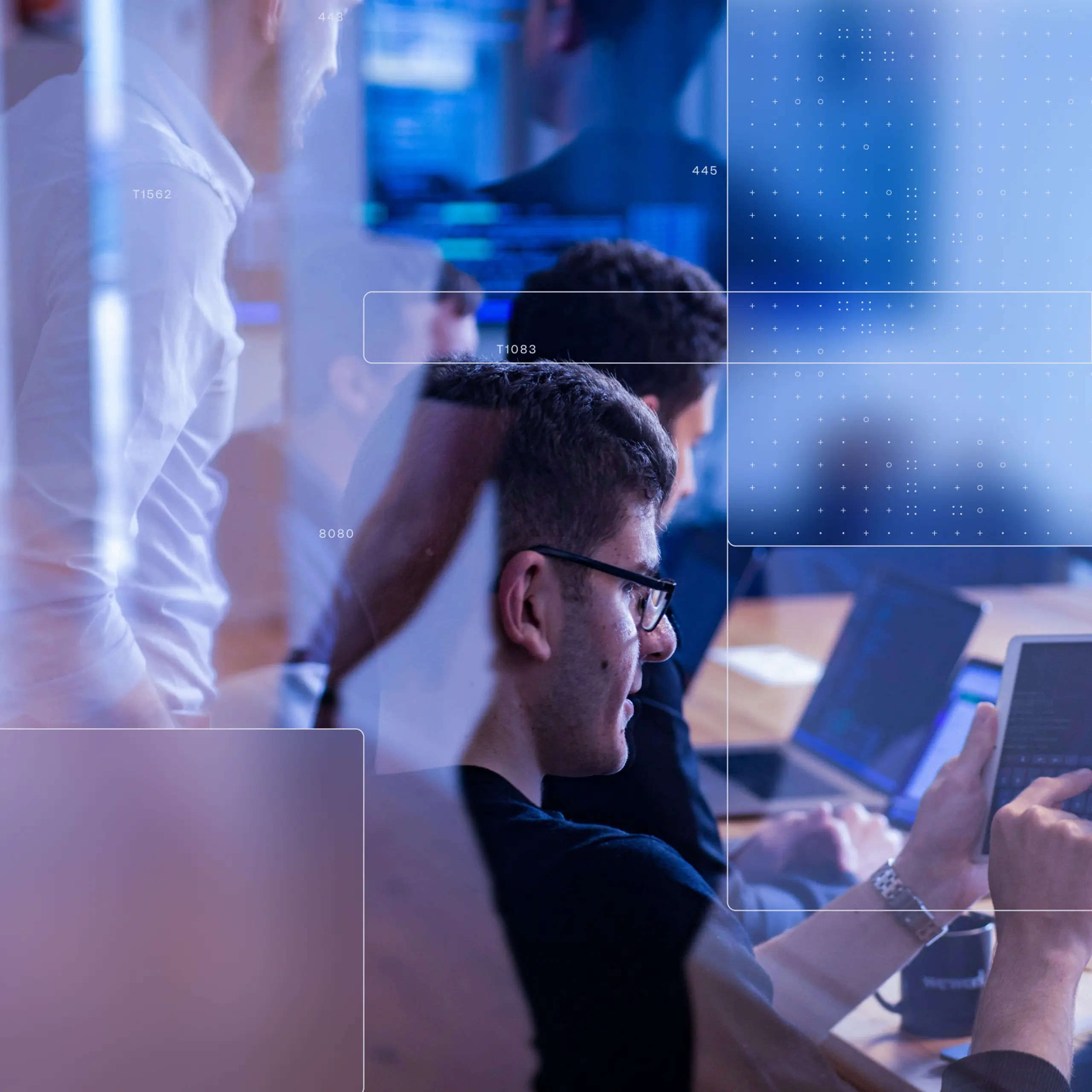 Blue-lit office scene with people gathered around laptops and monitors, overlaid with translucent interface graphics and dotted digital patterns